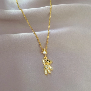 Close-up of gold titanium necklace featuring a sparkling crystal bear and star pendant