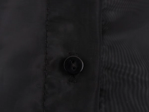 Close-up of a elegant black button on textured organza fabric with precise stitching