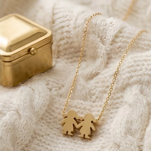 Close-up of golden necklace with two little girls pendant on a white knit sweater