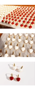 Close-up of red and white enamel heart hoop earrings with polished gold-plated finish