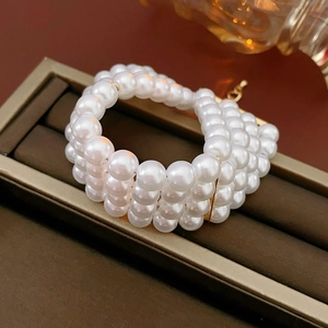 Détail du bracelet multicouche en perles blanches dans son écrin à bijoux marron