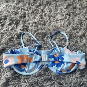 Detail of floral bikini top with underwire support and adjustable straps on plush surface