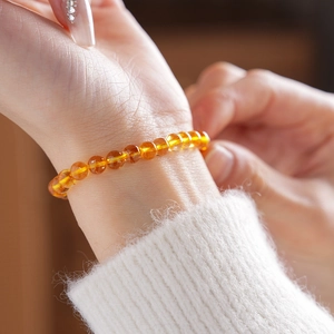 Detail of amber citrine beaded bracelet on wrist with white knitted sweater cuff