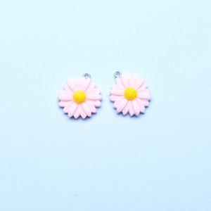 Detailed view of pink and yellow resin sunflower pendants with silver metal rings