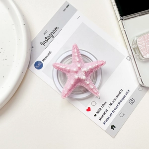 Close-up of pink starfish phone grip holder with matte texture on a stylish white desk