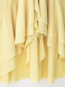 Detail of light yellow chiffon top featuring layered ruffles and soft fabric texture
