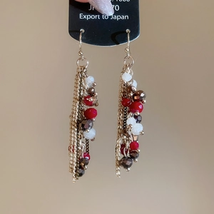 Detail of crystal bead fringe earrings with gold metal chains on a display card