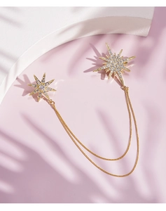 Detail view of gold star brooch set with rhinestones and elegant connecting metal chains