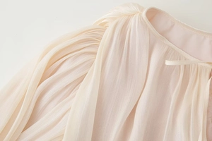 Dettaglio dello scollo a pieghe con laccetto delicato su abito in chiffon beige