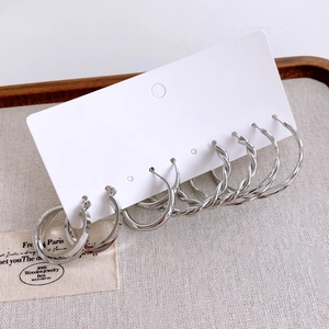 Set di tre paia di orecchini a cerchio in argento con trame a spirale su base di lino beige