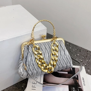 Silver pleated evening bag with gold chain handle and shoulder strap on white display