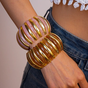 Detail of pink marble resin and amber brown acrylic chunky stretch bracelets with gold metal