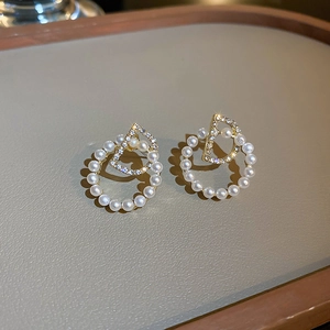 Gros plan de boucles d'oreilles créoles perle lettre D dorées avec zircons brillants