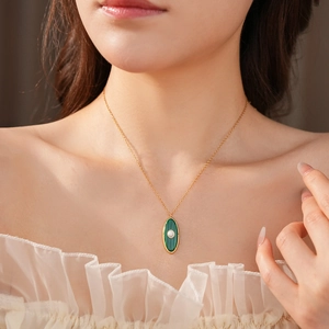 Close-up of vintage gold necklace with green malachite oval pendant on a model