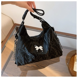Detail of black pleated PU leather shoulder bag featuring a silver butterfly buckle