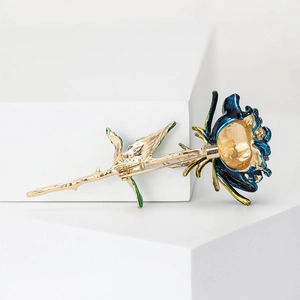 Elegant gold-tone rose brooch with deep blue enamel petals and green leaf accents