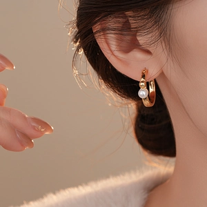 Gros plan de boucles d'oreilles créoles dorées en C avec perles portées par un mannequin