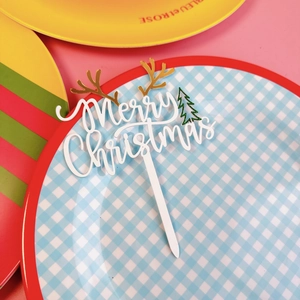Close-up of Merry Christmas acrylic cake topper with gold antlers and green tree