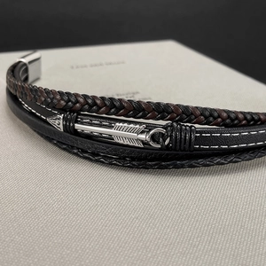 Macro shot of multi-layer braided leather bracelet with silver arrow detail and magnetic clasp