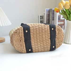 Handmade woven straw tote bag with black canvas straps and protective bottom metal studs