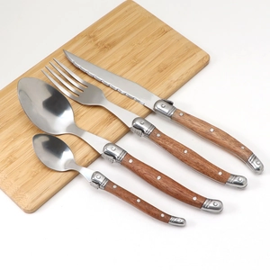 Detail of 4-piece stainless steel cutlery set with wood handles on a bamboo board