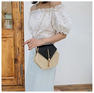 Detail of hexagonal straw woven crossbody bag with black leather flap and gold chain strap
