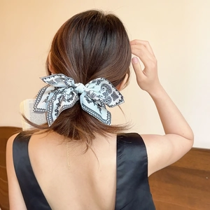 Detailed back view of a woman wearing a vintage paisley bow hair clip with a sleek black dress
