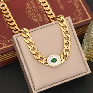 Detailed macro view of gold chunky chain necklace with green gem pendant on box