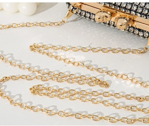 Close-up of sparkling rhinestone evening clutch with elegant gold chain and dual metal clasp