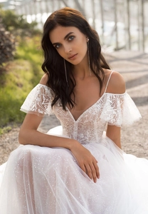Close-up of off-the-shoulder lace wedding dress with ruffled sleeves and sequined tulle