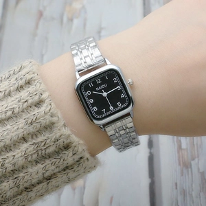 Elegant square silver stainless steel watch with black dial on a knitted sweater cuff