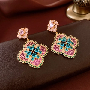 Macro detail of vintage floral earrings featuring blue and pink crystals on gold metal