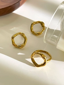 Detail shot of golden geometric hoop earring with irregular wave texture and high metallic shine