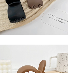 Detail view of matte black and brown small hair claw clips on a light wood tray