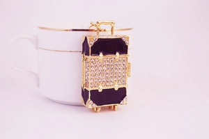 Detailed close-up of a luxury gold suitcase keychain with black finish and rhinestones