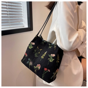 Detailed close-up of a black fabric tote bag featuring elegant floral embroidery patterns