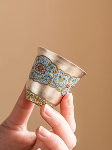 Macro detail of enamel cloisonné silver tea cup with blue floral patterns and gold trim