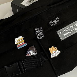 Cartoon enamel cat pins with book and coffee themes attached to a black canvas bag