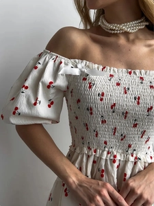Detail of square neckline with cherry print, ruffled edges and a white satin bow