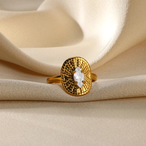 Detail of gold hammer textured ring with marquise cut gemstone on beige silk fabric