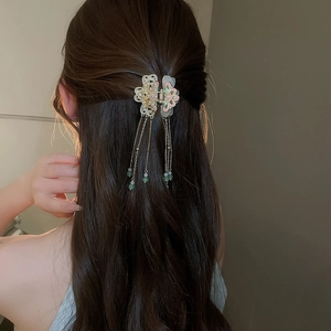 Detailed view of flower hair clip with long metal tassels on model's hairstyle