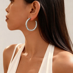 Close-up of model wearing silver textured C-shaped hoop earrings with geometric pattern