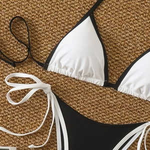 Detailed top view of a black and white contrast bikini set on a textured straw mat