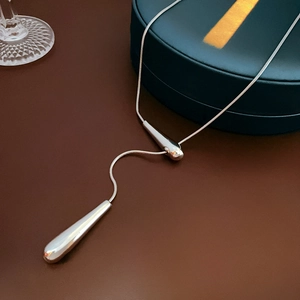 Gros plan de pendentifs goutte d'argent sur une chaîne élégante sur un écrin à bijoux