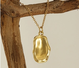 Detailed close-up of a golden irregular textured pendant hanging on a wooden branch