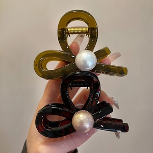 Detail shot of elegant tortoiseshell and black pearl hair claws held in hand