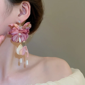 Close-up of purple fabric flower earrings with long pearl tassels worn by a model