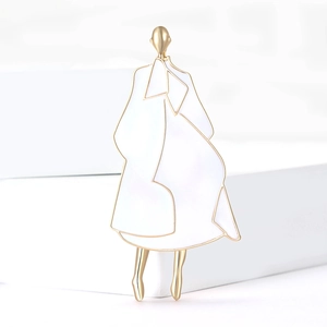 Detail of creative enamel brooch featuring a minimalist lady in white coat with gold trim