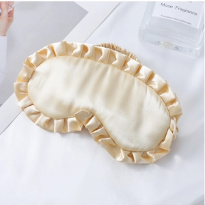 Detail der champagnerfarbenen Satin-Schlafmaske mit Rüschenrand und elastischem Kopfband