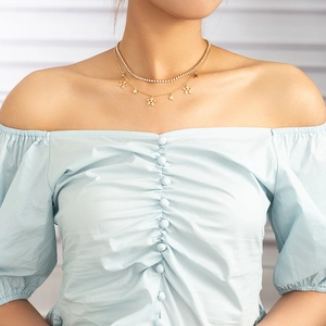 Close-up of double-layered gold necklace with sparkling star charms and crystal tennis chain